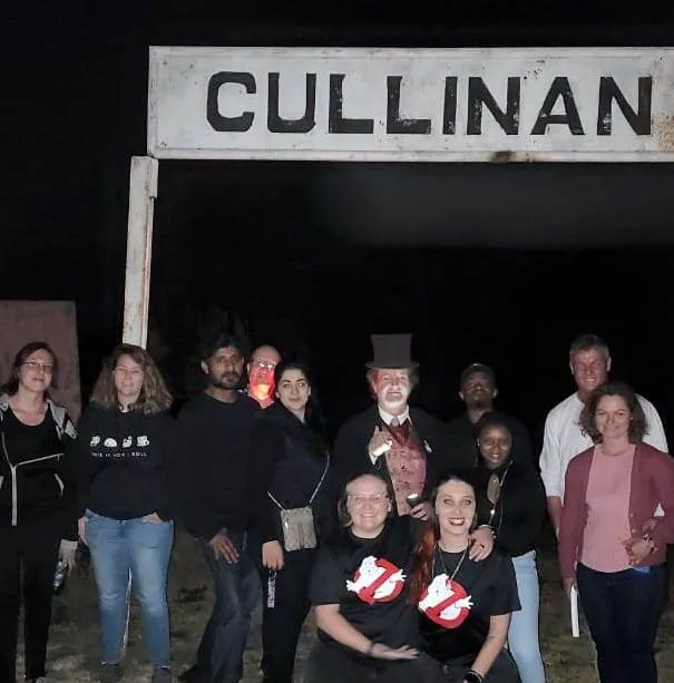 Tour guests gathered beneath the Cullinan station sign at night