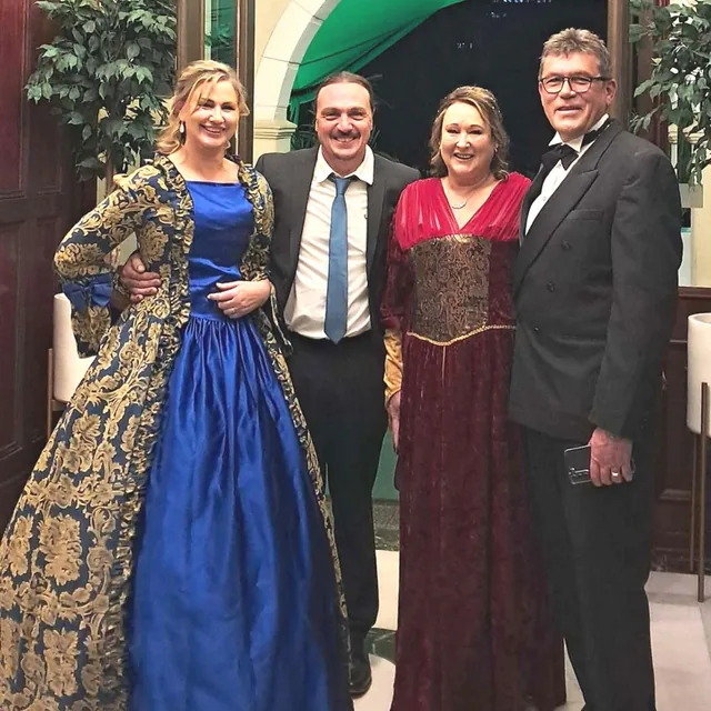 Four dinner-show guests wearing formal and Victorian-inspired evening clothes