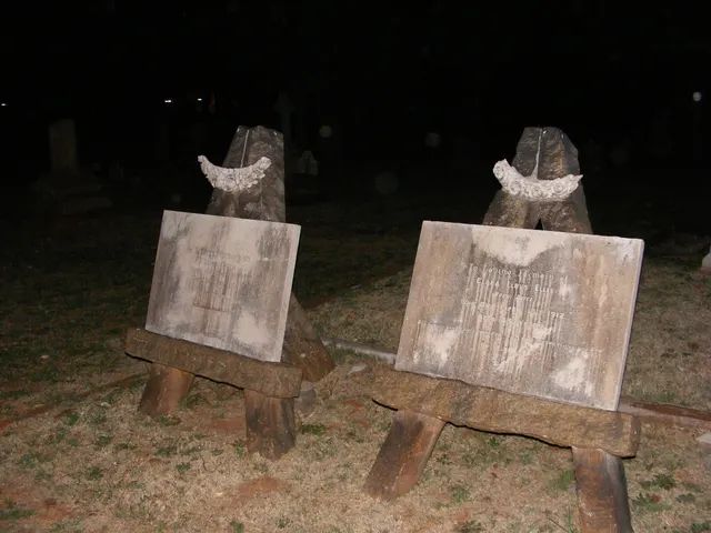 Two weathered stone headstones photographed at night