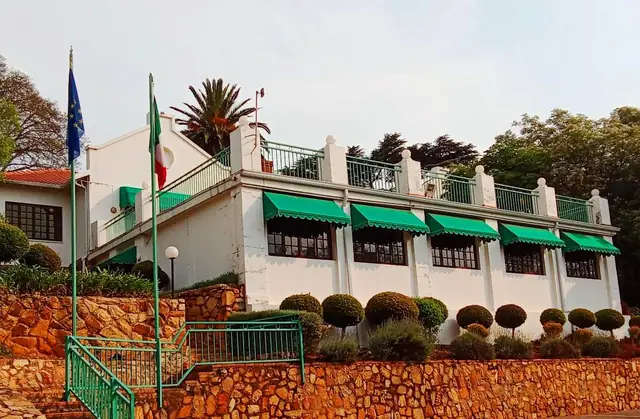 Historic building with a veranda, green awnings and garden