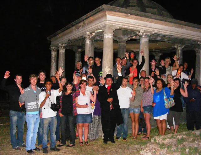 Tour guests beside a columned memorial at night