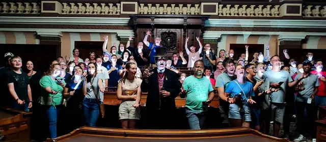 A large group of guests gathered inside a historic room
