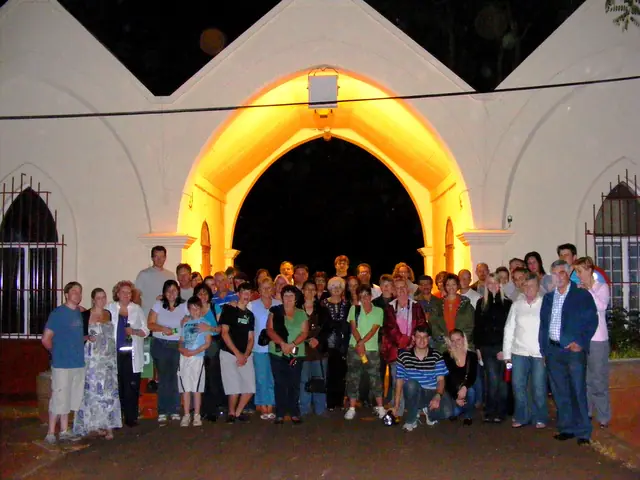 A large tour group beneath an illuminated arch at night