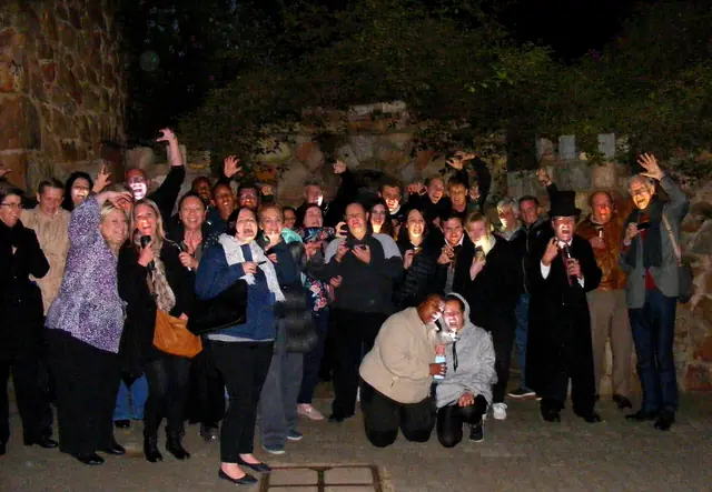 Tour guests beside historic stone walls at night