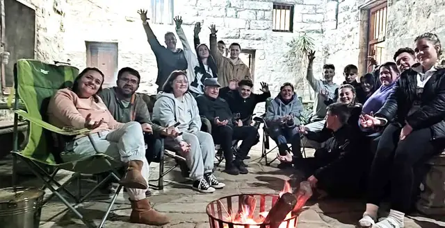 Guests seated around a fire in a stone courtyard