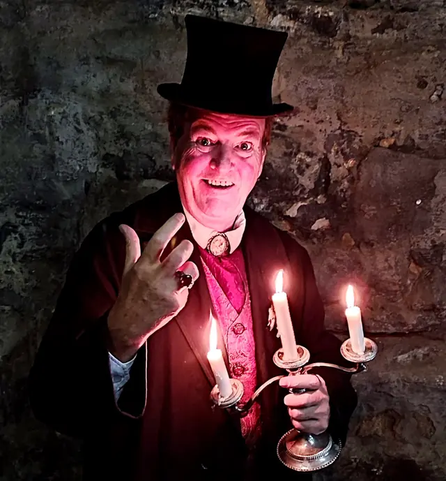 Mark Rose-Christie in a top hat holding a lit candelabra