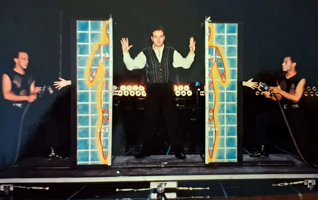Mark Rose-Christie performing an illusion with two assistants on stage