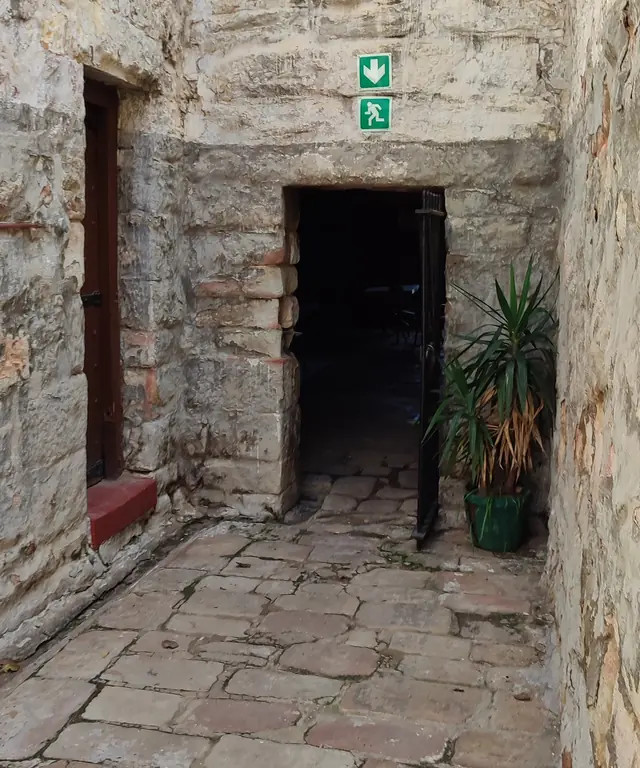 Stone passage leading to a dark open doorway
