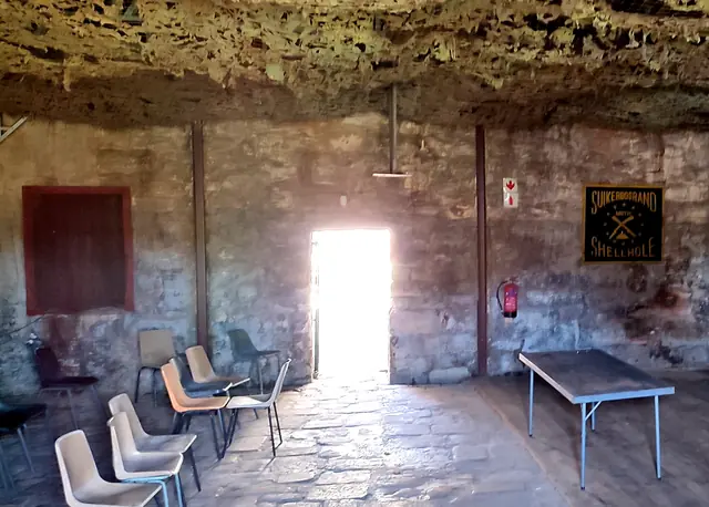 Stone-walled room with chairs and a bright open doorway